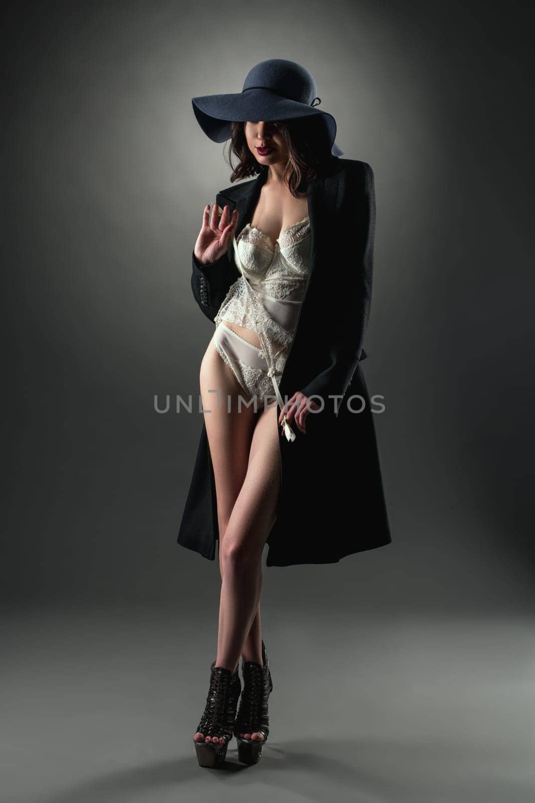 Model dressed in sexy lace lingerie, coat and hat by rivertime