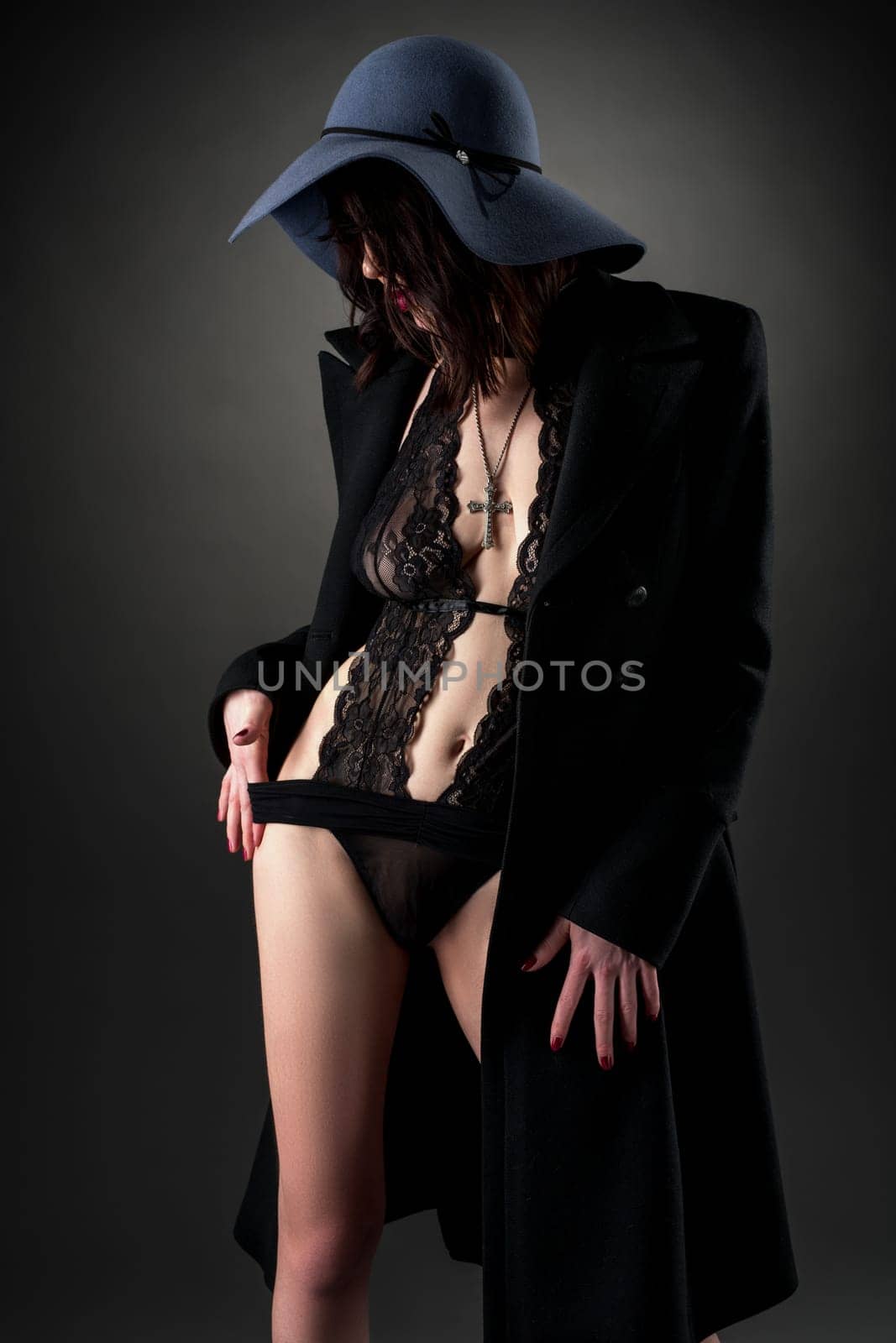 Stylish model dressed in lace bodysuit, coat and hat