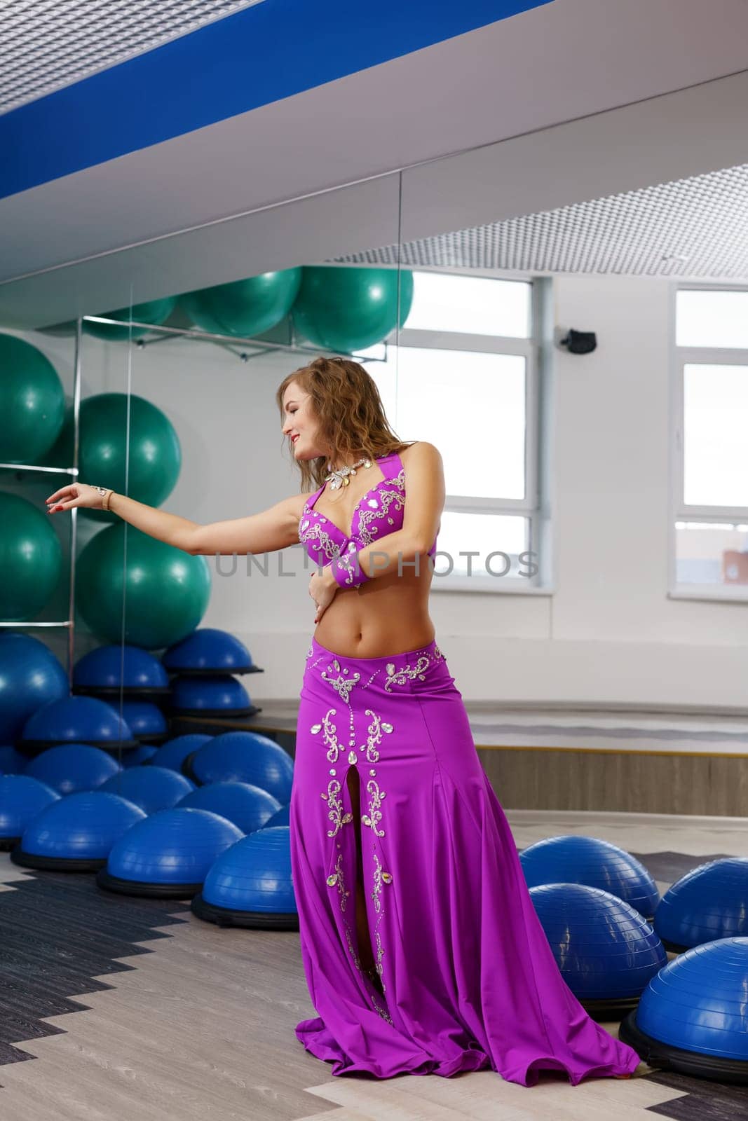 In gym. Image of beautiful belly dancer posing at camera