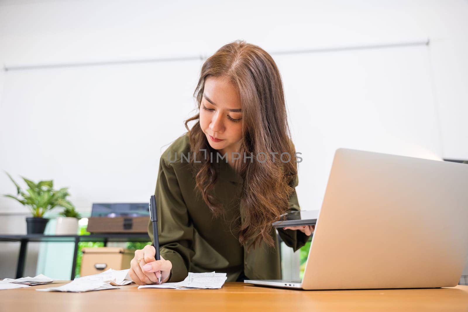woman working with financial data she calculator with tablet computer and writing make note calculate by Sorapop