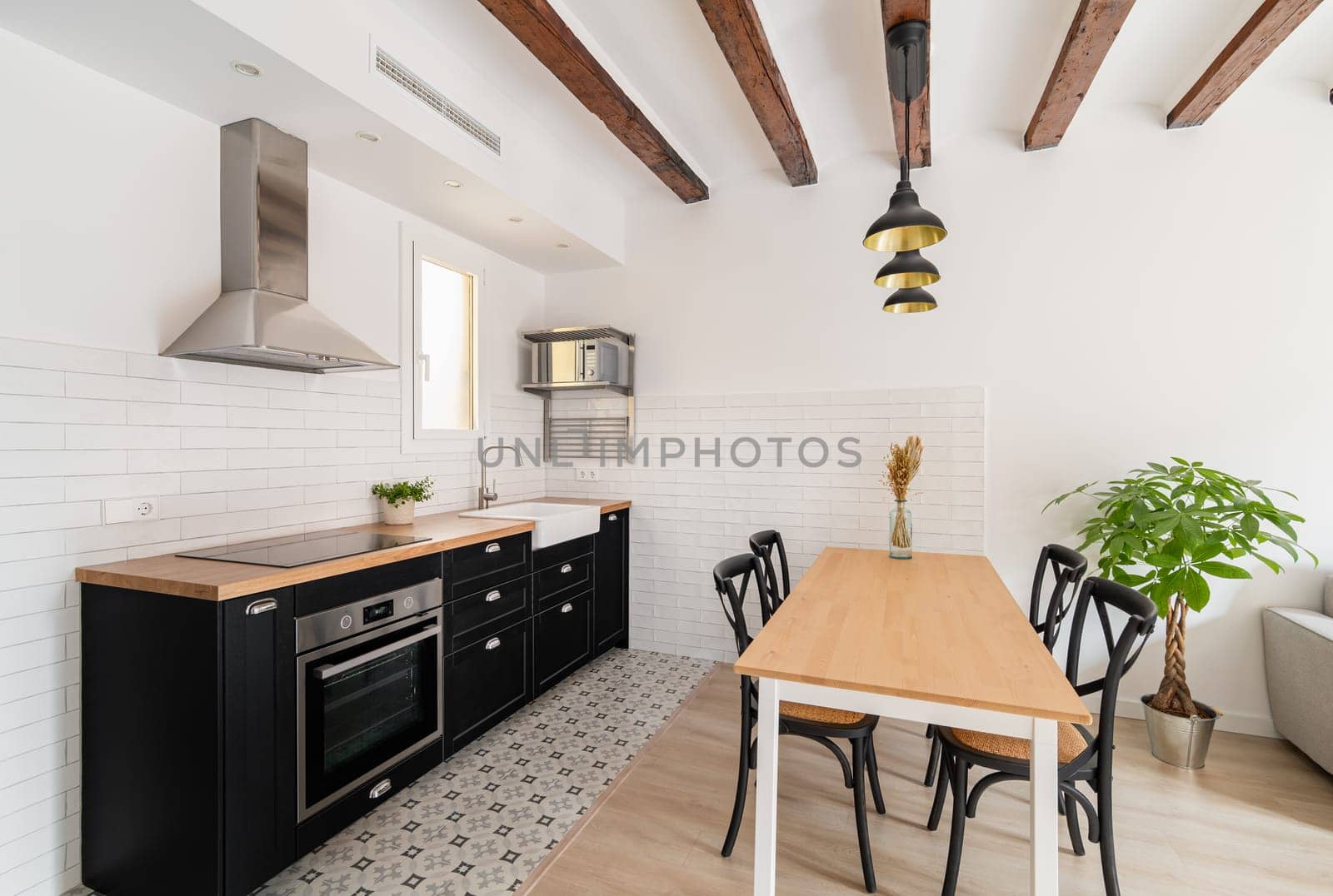 Cozy kitchen with wooden dining table and appliances in studio apartment. Comfortable cooking area with place to eat in house. Home interior