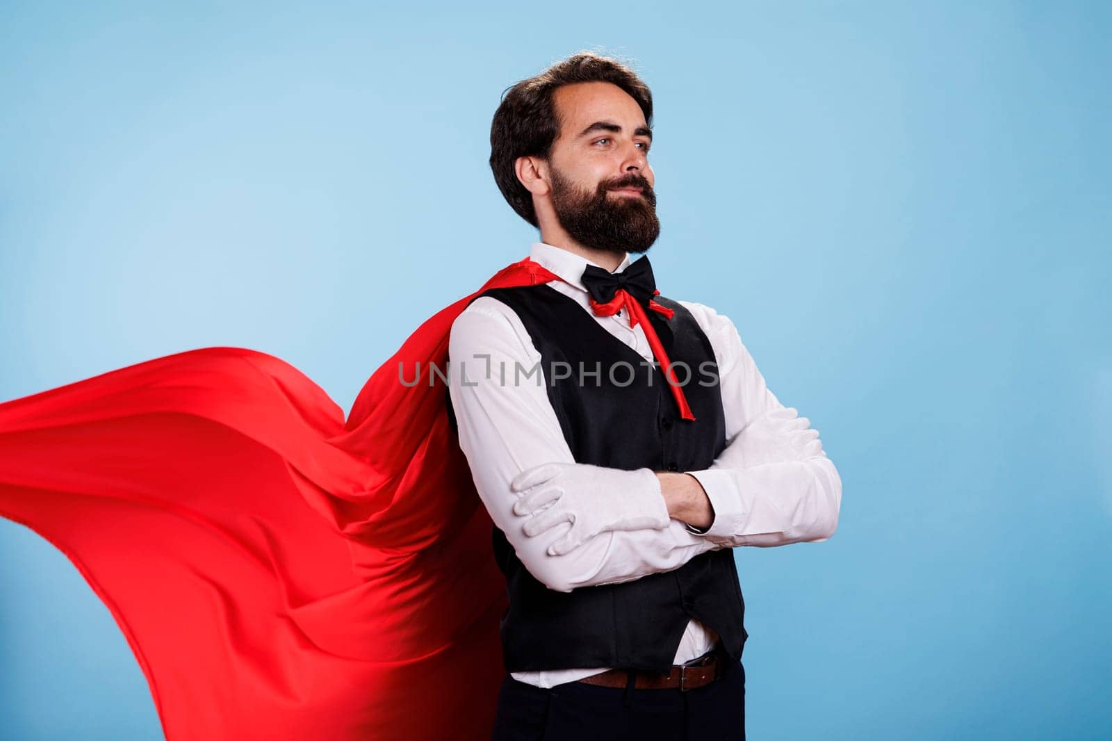 Person wearing red cape and formal suit posing with confidence, feeling determined to help and save people. Young man pretending to be fantasy cartoon superhero with mantle, superhuman.