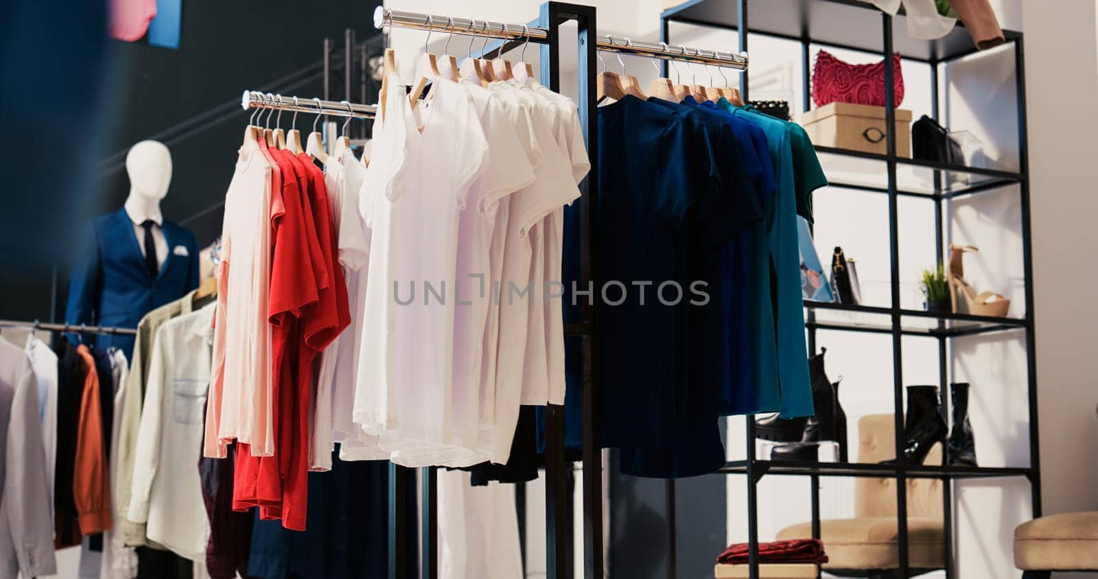 Modern boutique filled with casual wear, multiple racks with fashionable merchandise. Interior of empty clothing store with new fashion colletion on hangers. Small business concept.