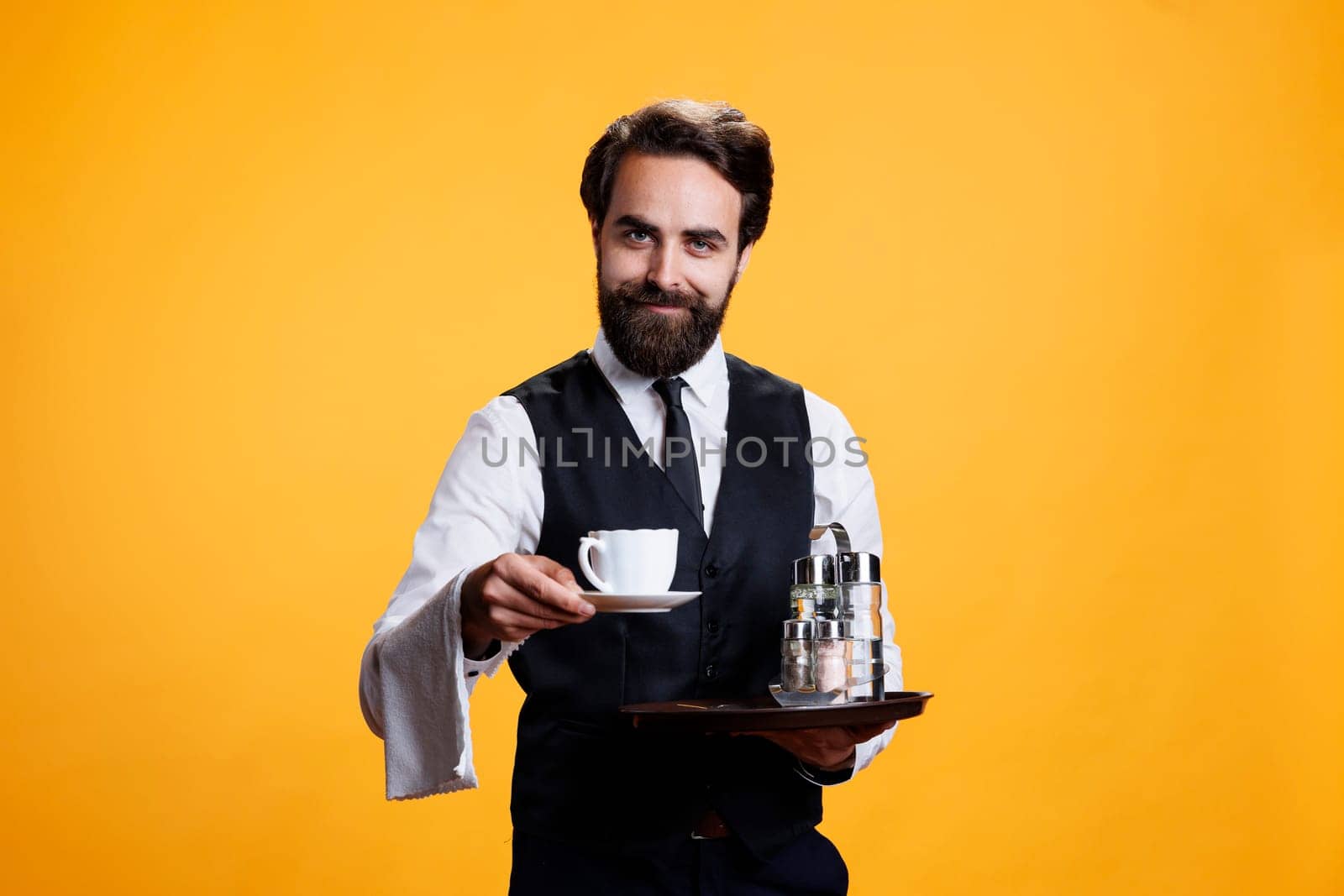 Elegant butler giving coffee cup to clients, pretending to serve people while he holds platter with salt and pepper. Professional expert waiter with suit and tie carrying tray, catering industry.