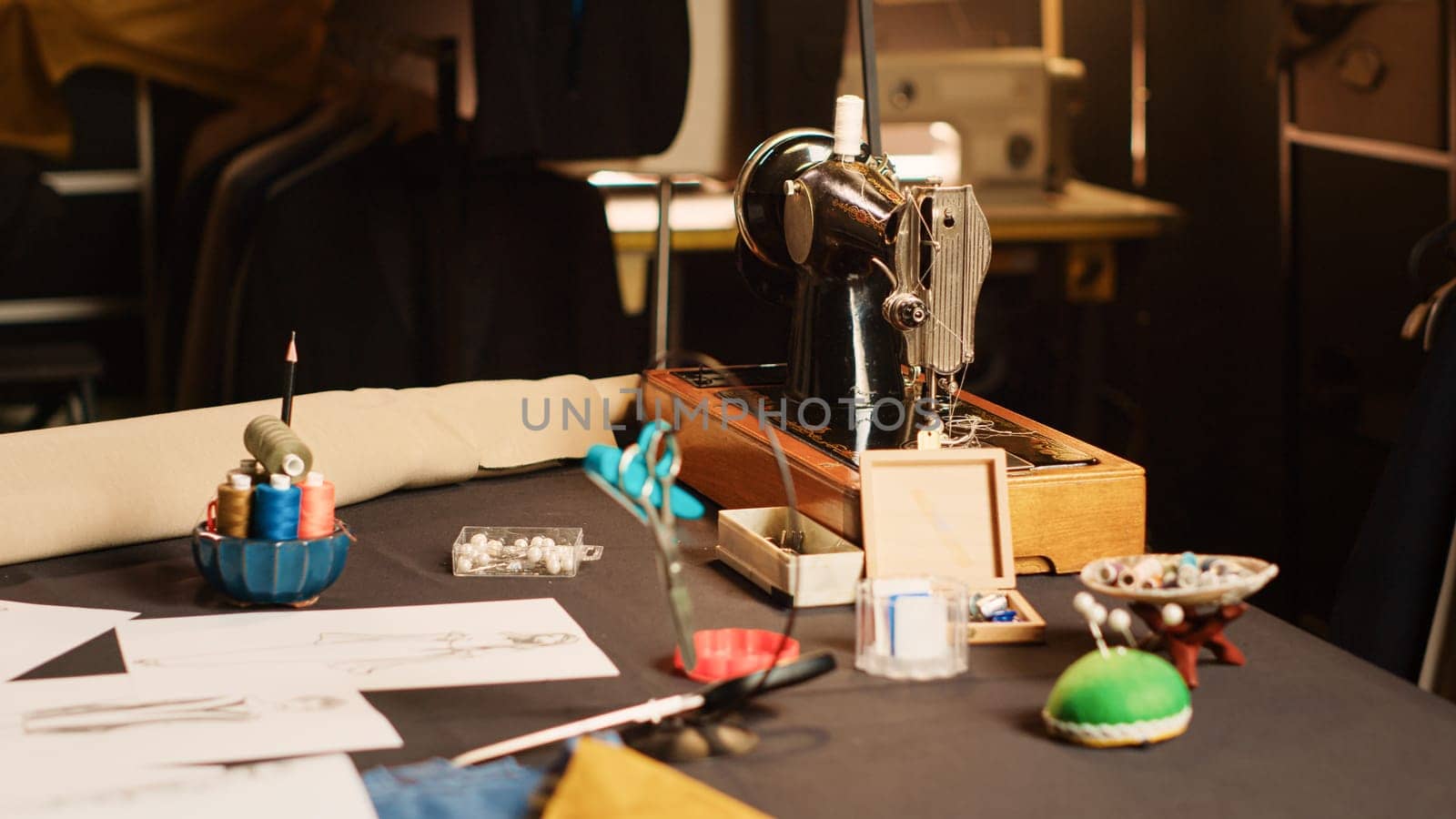 Industrial sewing machine and needles in fashion atelier, luxury craftsmanship with tailoring industry tools in workshop. Workstation with fabric and garments, manufacturing process. Close up.