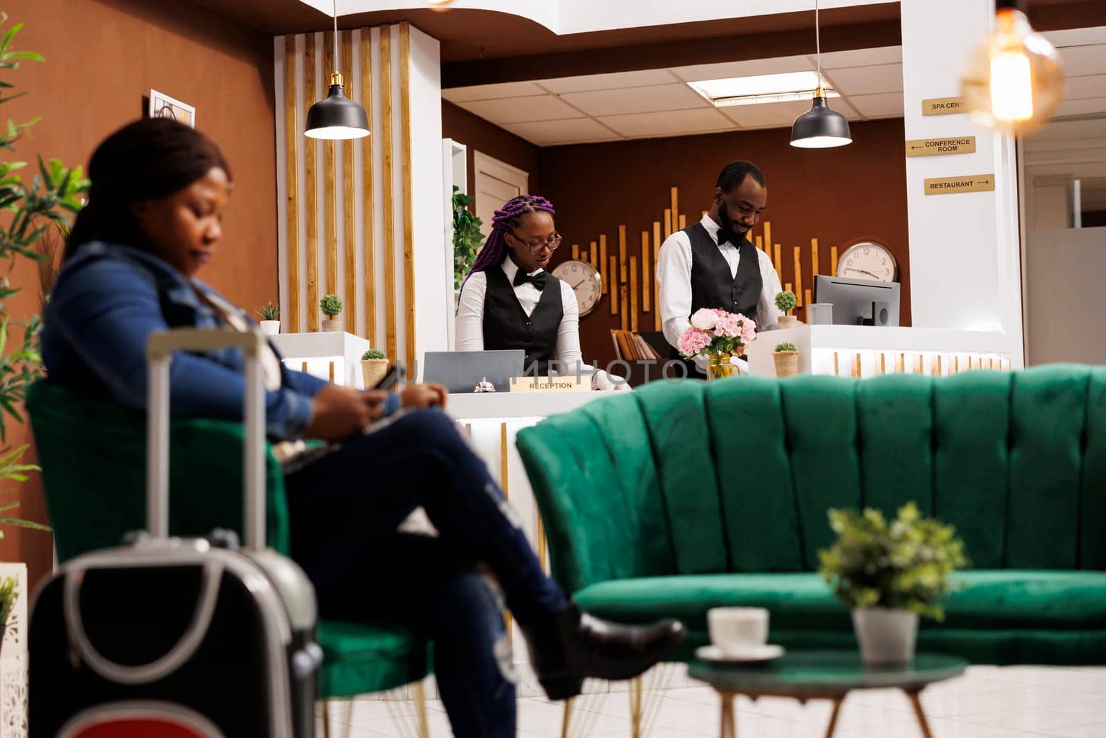 African American front desk staff working together behind reception counter, maintaining guest records and book reservations, hotel employees waiting for tourists at resort. Hospitality industry