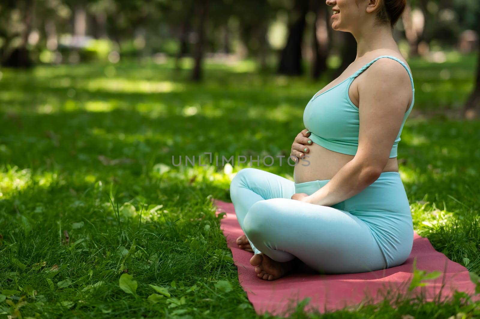 Close up belly of pregnant woman doing yoga outdoors