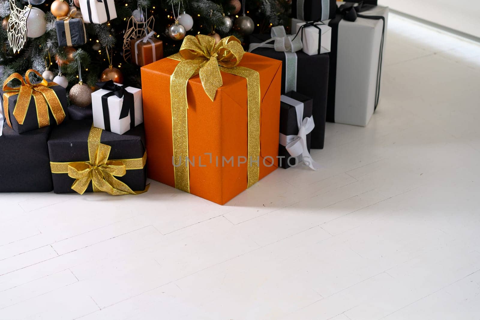 Christmas present gift box stacked close up. Holiday sale concept. Many gift box black, white, orange color with gold ribbon and light garland