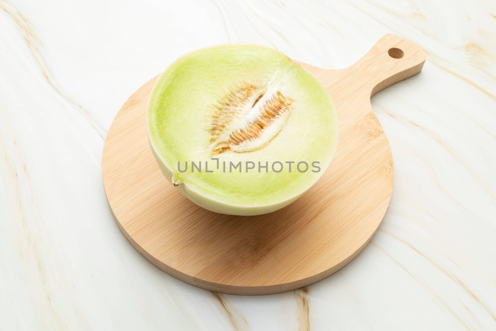 Cut Organic Honeydew Melon On Wooden Cutting Board on Granite Table, Cucumis Melo Inodorus Group. Ripe Nutritious Summer Juicy Fruit. Horizontal Plane. Harvesting, Top View by netatsi