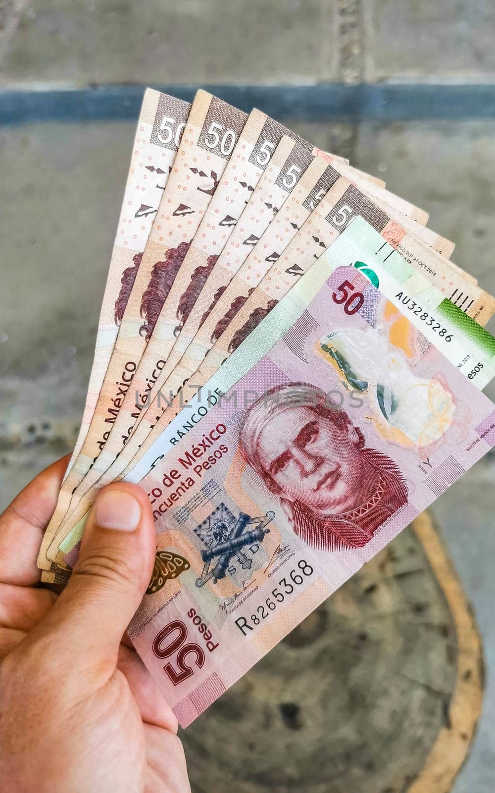 Money Mexican peso bills in hand in Puerto Escondido Mexico. by Arkadij