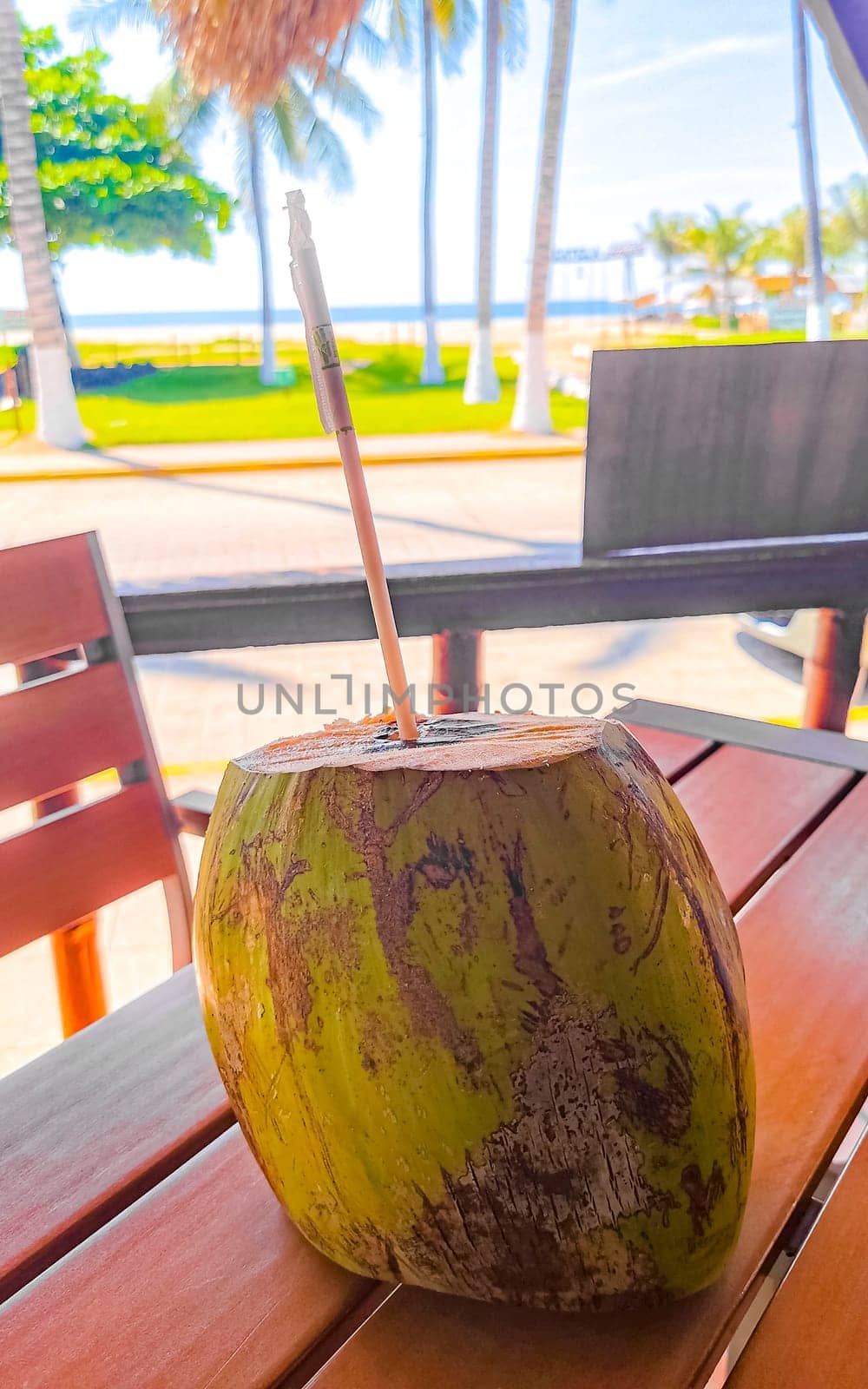 Tropical coconut with straw on the table in Zicatela Puerto Escondido Oaxaca Mexico.