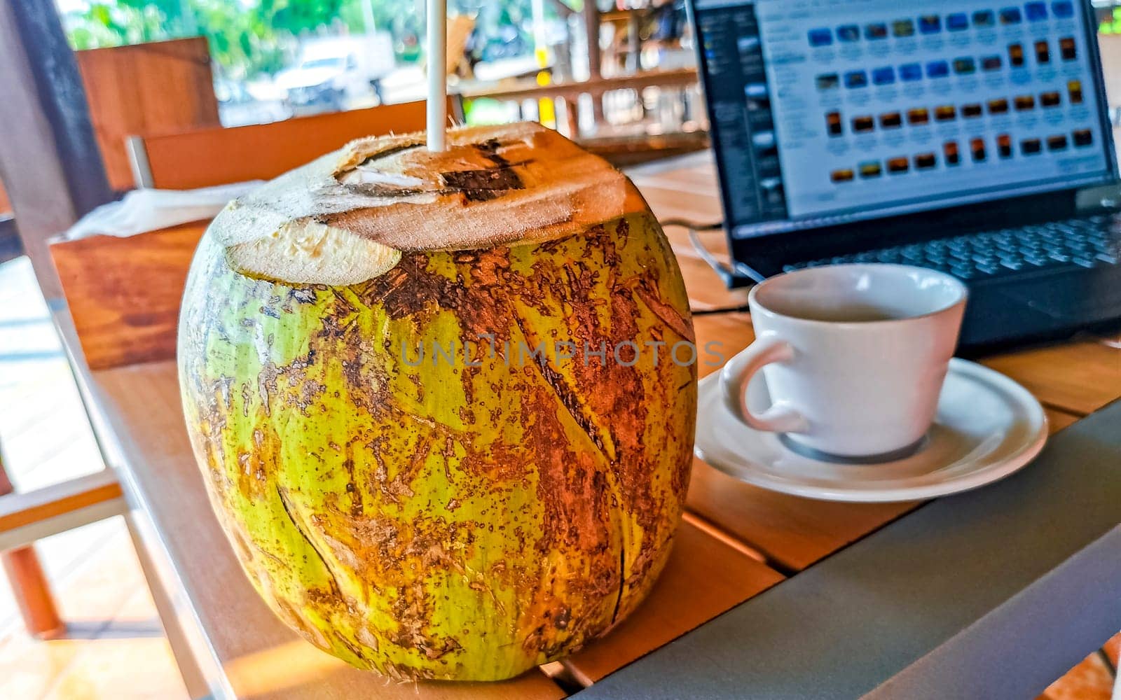 Tropical coconut with straw on the table Puerto Escondido Mexico. by Arkadij