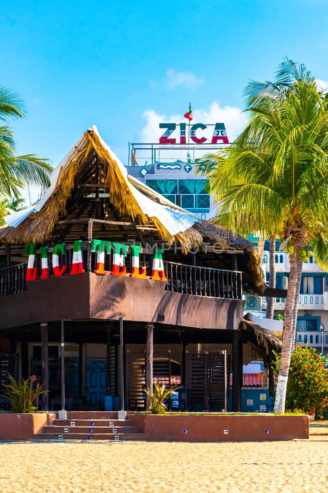 People parasols bars restaurants loungers beach palms Zicatela Mexico. by Arkadij