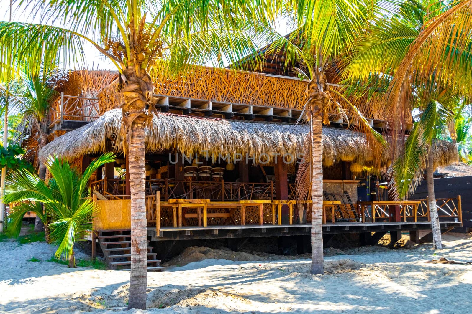 People parasols bars restaurants loungers beach palms Zicatela Mexico. by Arkadij