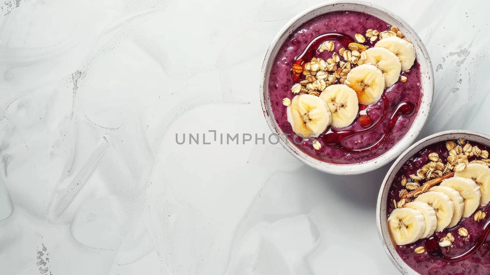 Two bowls of superfood smoothie with bananas, granola crumble, and fresh fruit on a table AIG50