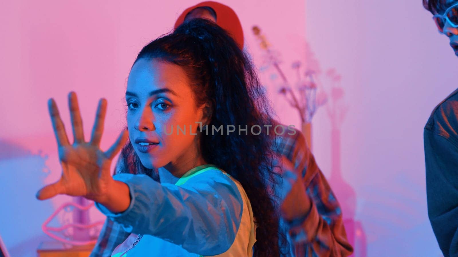 Close up of break dancer team dancing together at modern studio with pink led light. Multicultural people moving to hip hop music while wearing stylish fashion cloth. Crazy, funny mood. Regalement.