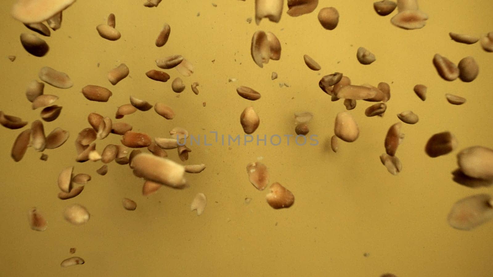 Slow motion of flying peanut snack in air to camera with yellow background. Close up of snack explosion captured with dramatic black background. Each close-up shot of a variety of snacks. Comestible.