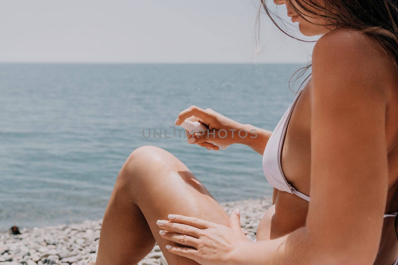 Woman sunscreen sea. Close up of happy smiling woman is applying sunscreen or sun tanning lotion on body to take care of her skin on seaside beach. Female On Sea Vacation Holiday Resort. Slow motion