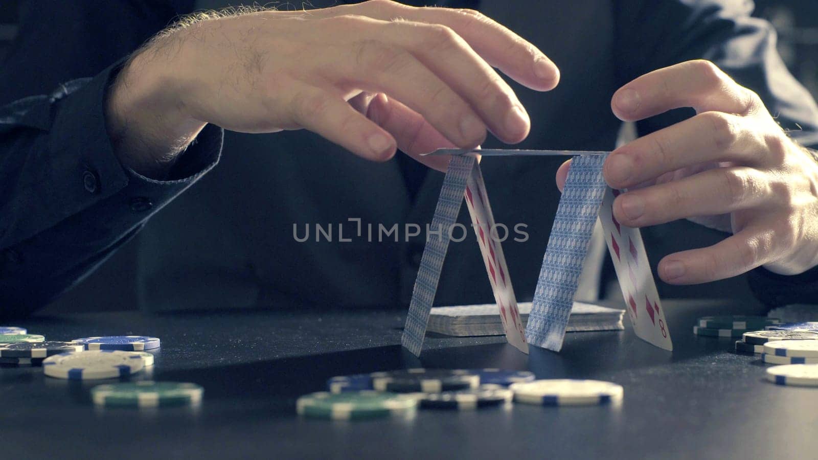 Man's hands building a house of a playing cards. Close up