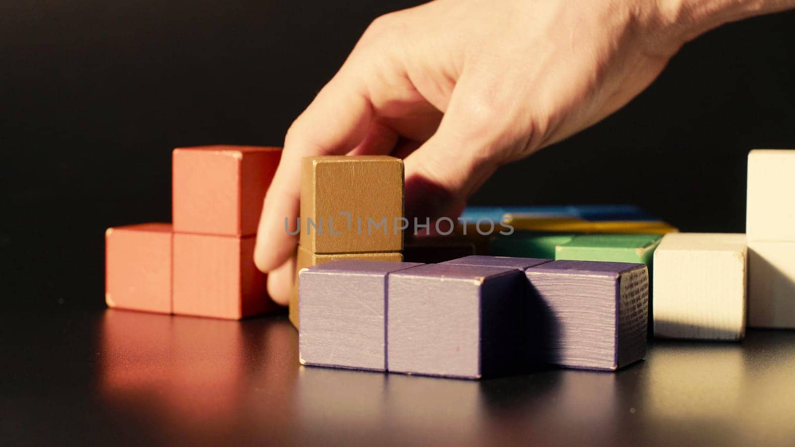 Man's hand picking colored cubes. 3D tetris by Chudakov