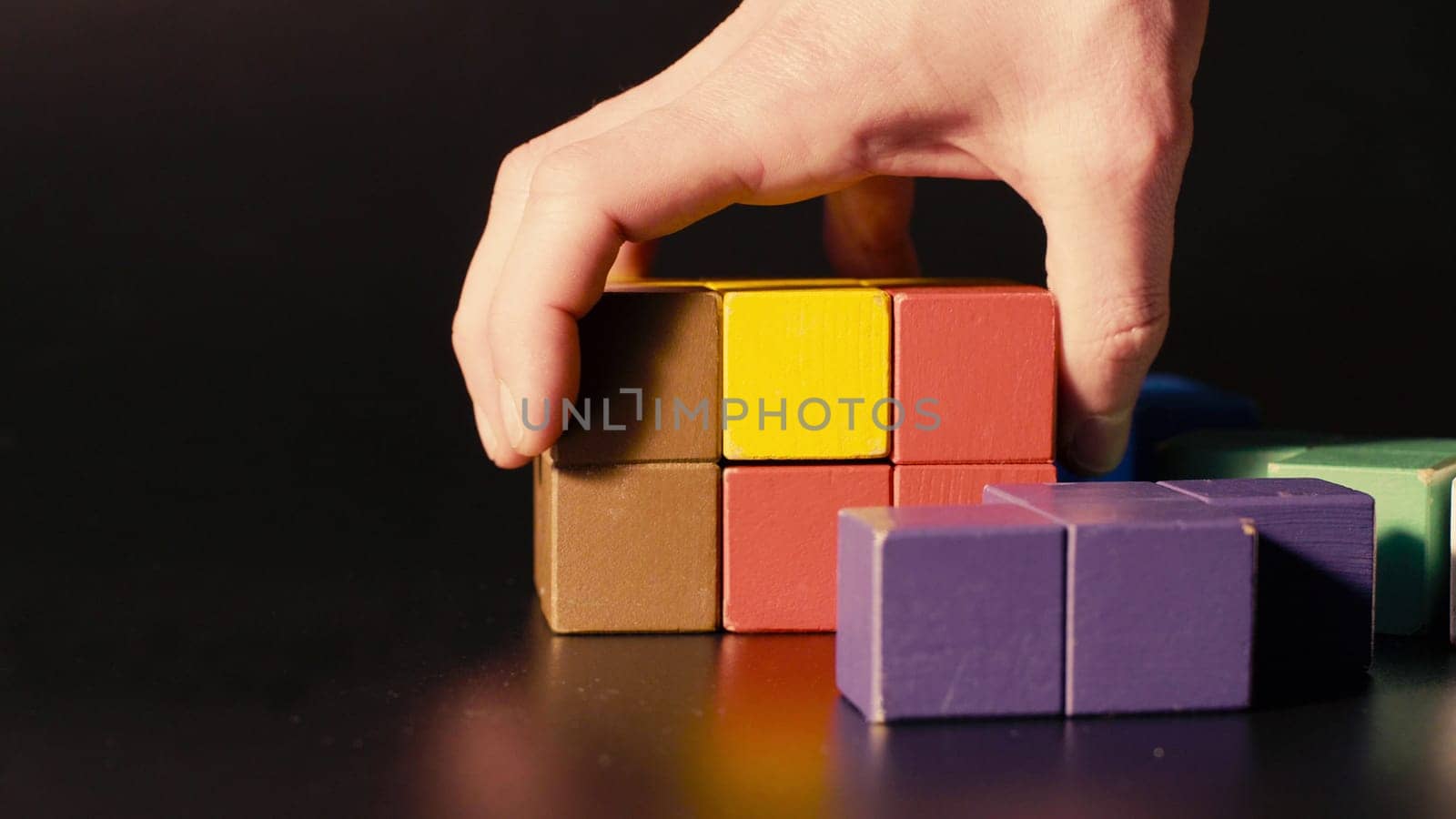 Man's hand picking colored cubes. 3D tetris by Chudakov