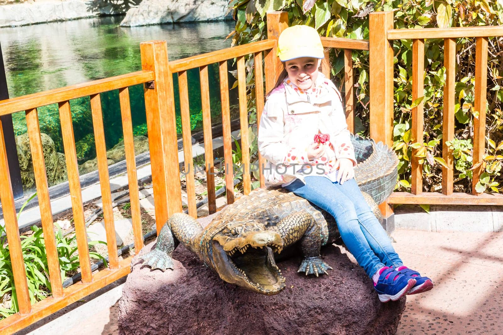 little girl at the zoo with the monument of a crocodile.