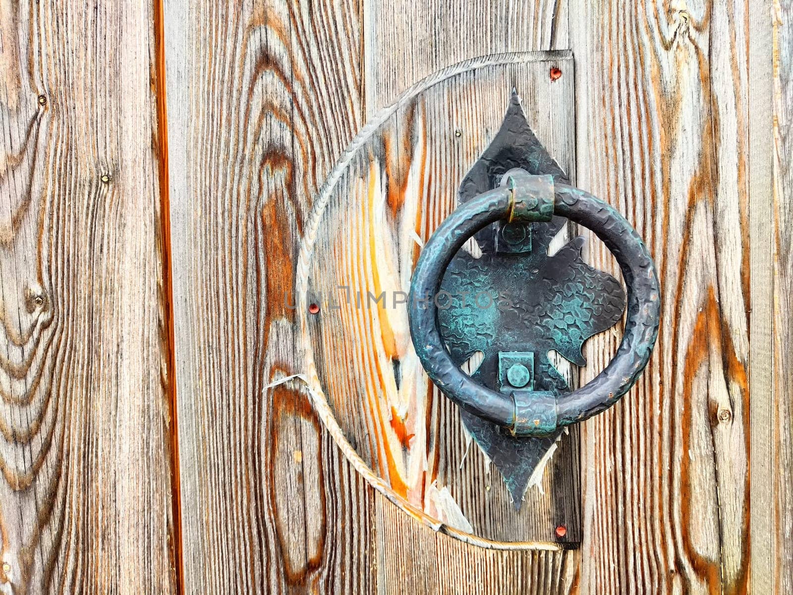 Forged metal handle on a wooden door. Background, texture. Antique Forged Metal Handle on Rustic Wooden Door by keleny