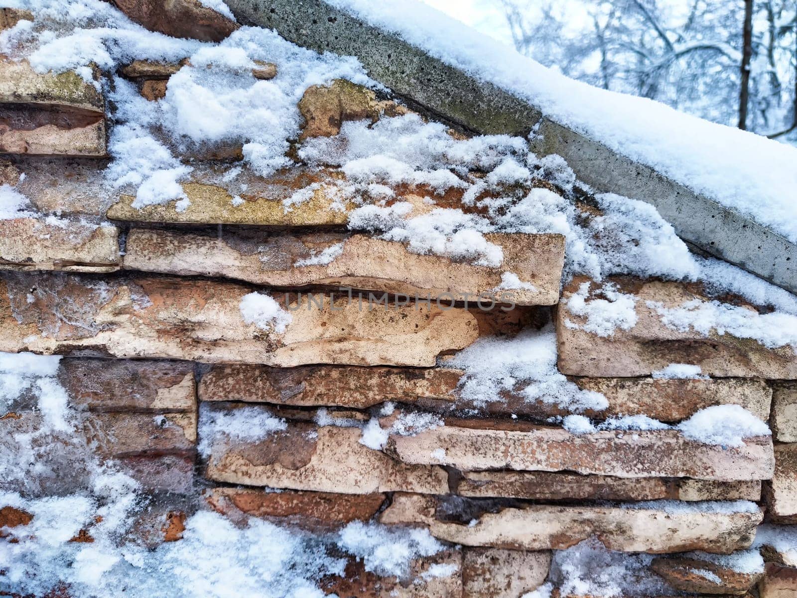 Snow rests on the textured surface of a brick wall. Background, texture, pattern, copy space