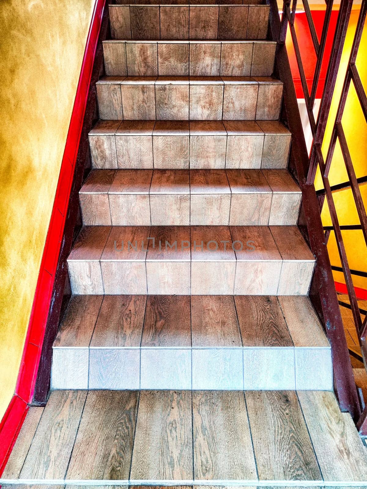 Warmly Lit Wooden Staircase With Red Handrails. A staircase with wooden steps and bright red handrails by keleny