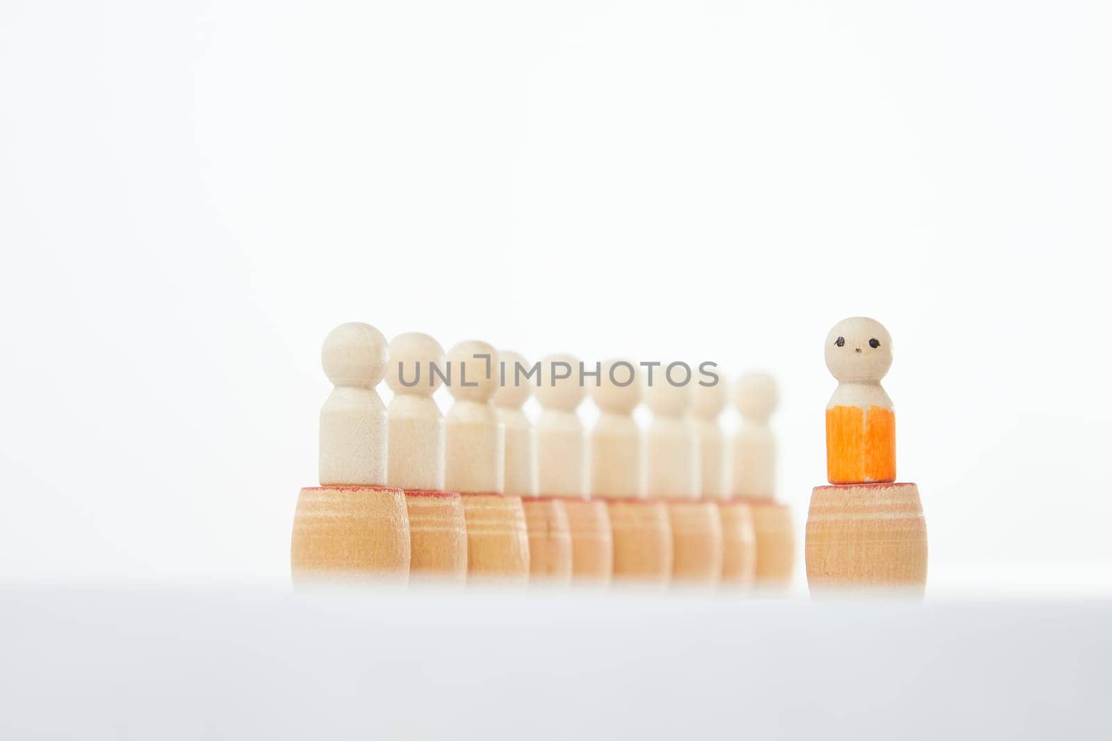 Wooden figurines with a leader and a group with partial focus. The concept of distinguishing a leader from the crowd. Sighted, intelligent, different among the blind group by keleny