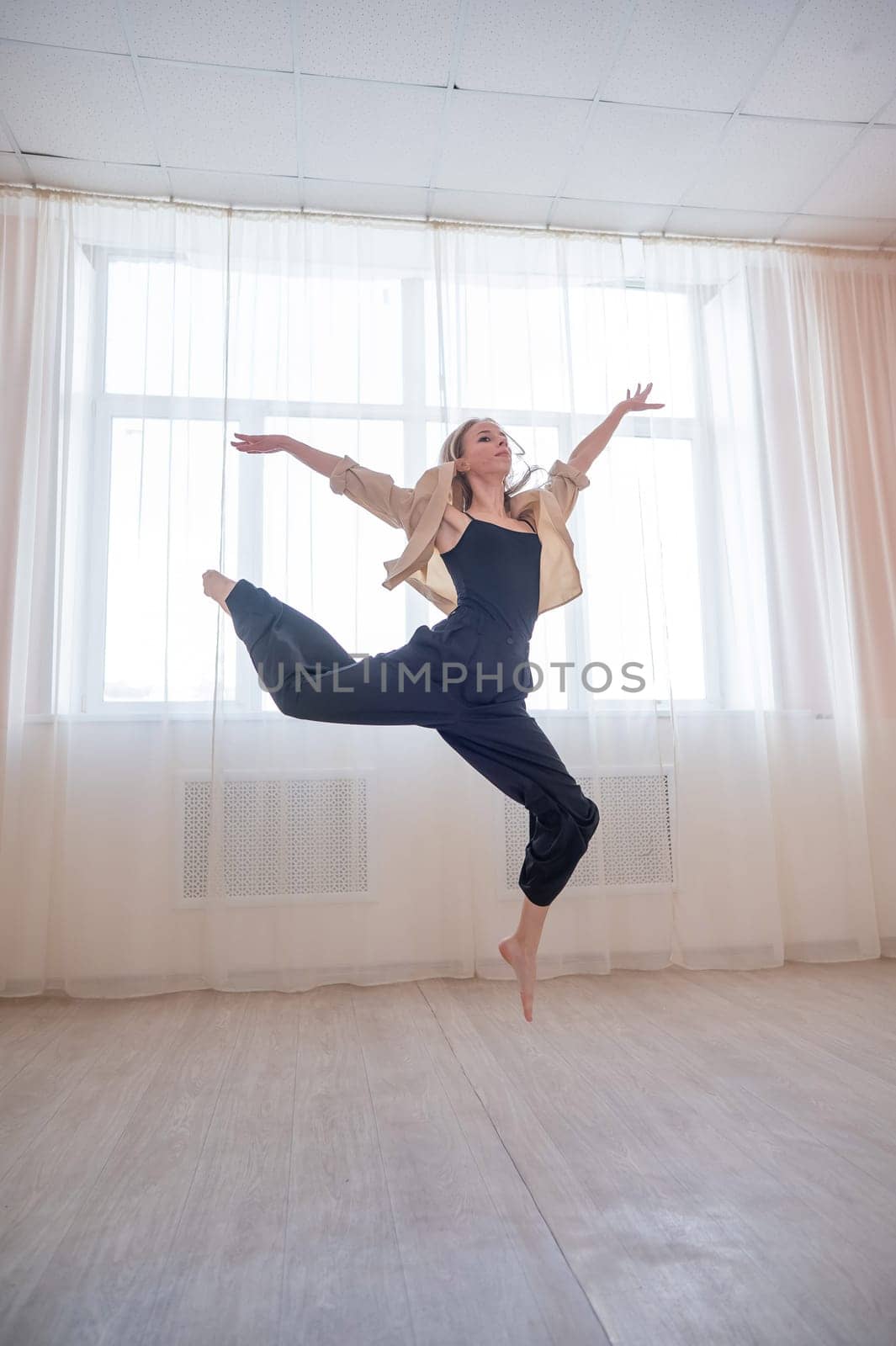 Caucasian woman dances contemporary in ballet class. Dancer in a jump. Vertical photo. by mrwed54