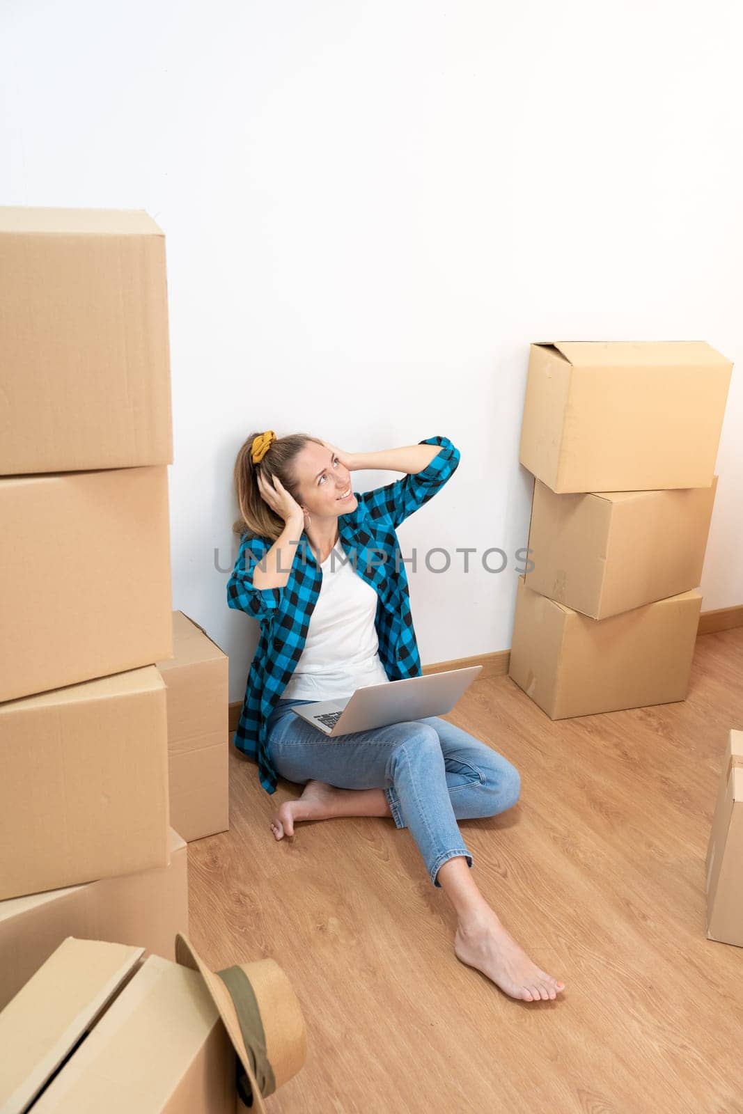 Happy woman sitting on the floor with many boxes, listening music with headphones in a new house. by PaulCarr