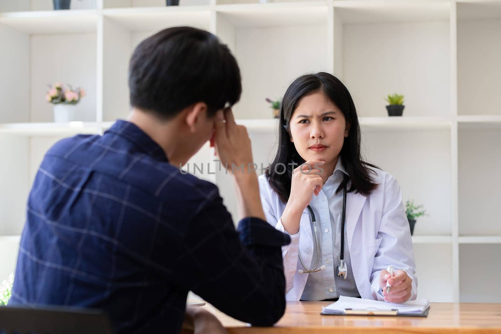 Female doctor gives advice to young patient who is stressed and has health and medical problems in clinic.