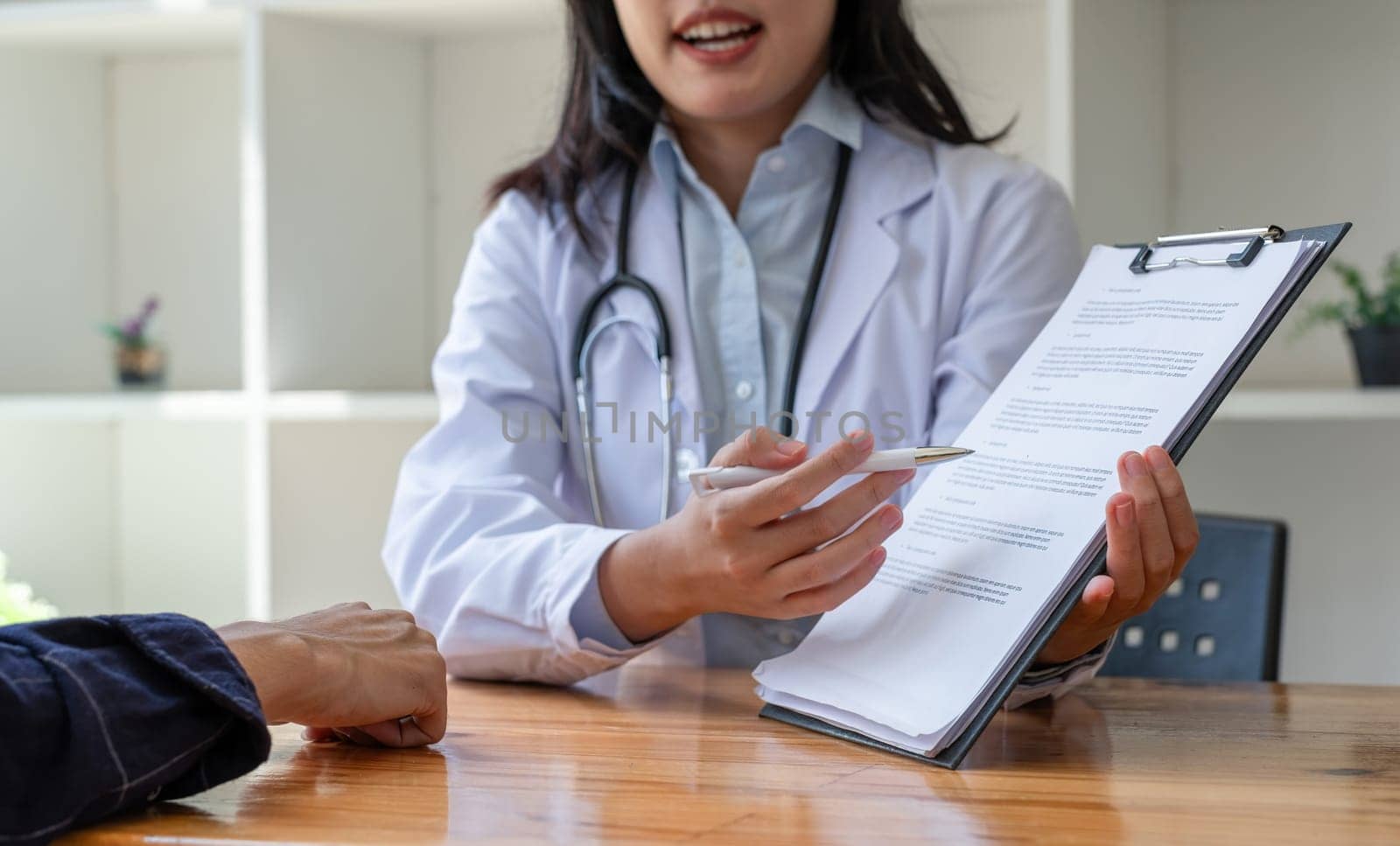 Female doctor giving advice to young patient about health and healthcare in clinic by wichayada