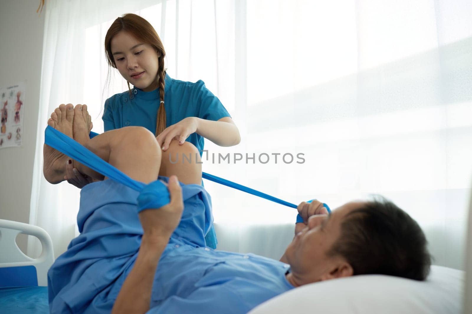 a woman in a blue uniform helps a man in a hospital bed by wichayada