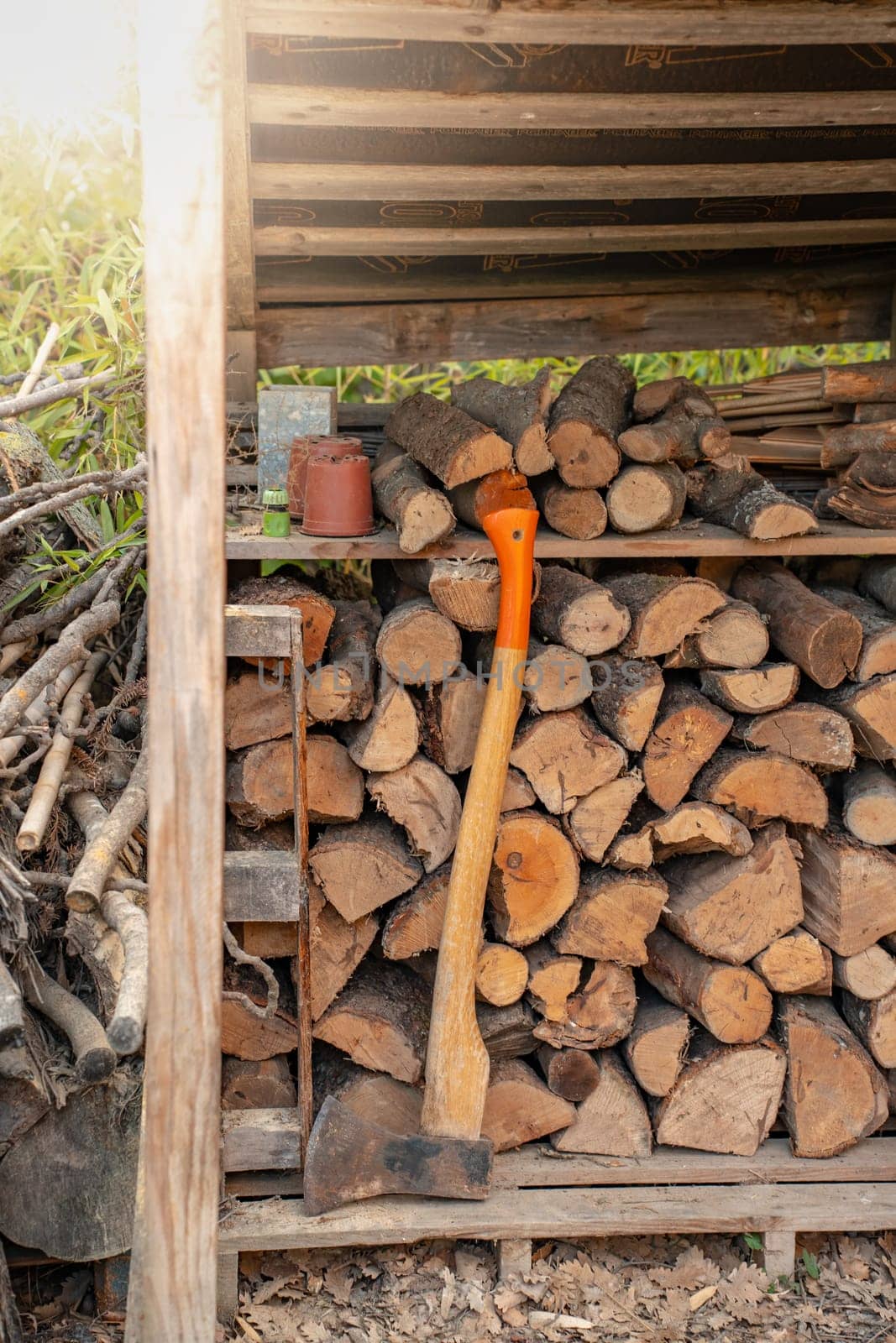 Axe in front of a pile of wood in a woodshed. Natural background. High quality photo