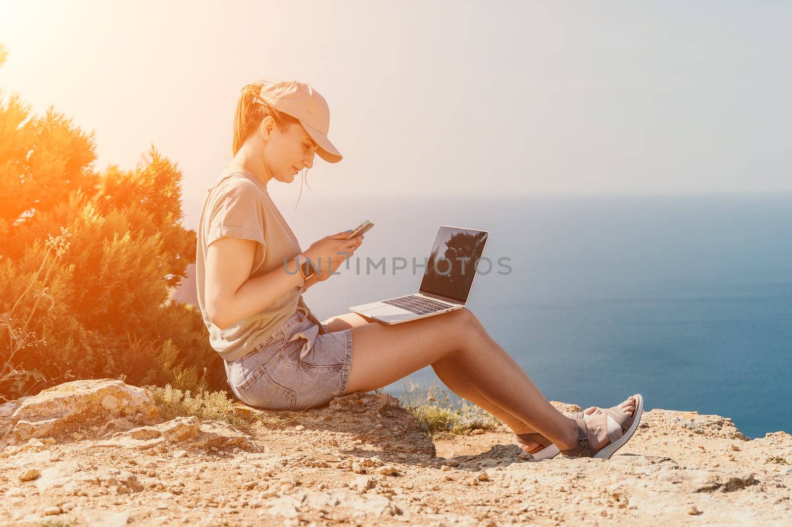 Woman sea laptop. Business woman, freelancer with laptop working over blue sea beach. Happy smiling girl relieves stress from work. Freelance, remote work on vacation, digital nomad, travel concept by panophotograph