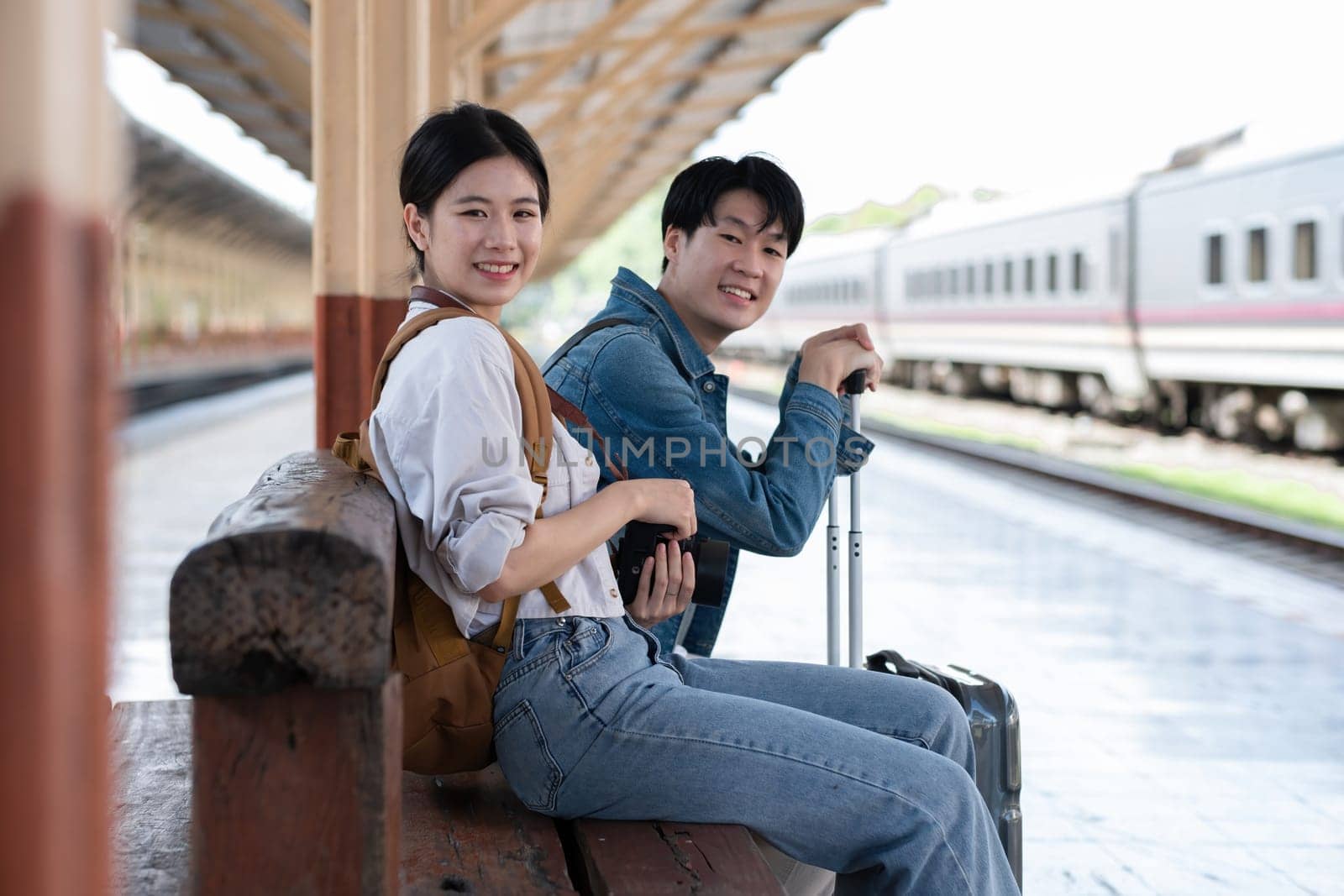 A young Asian couple waits for their train together at the train station, waiting to travel..