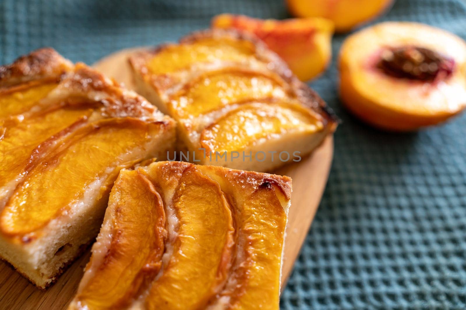 A dessert made of sliced peaches is on a wooden cutting board. The dessert is covered in sugar and looks delicious