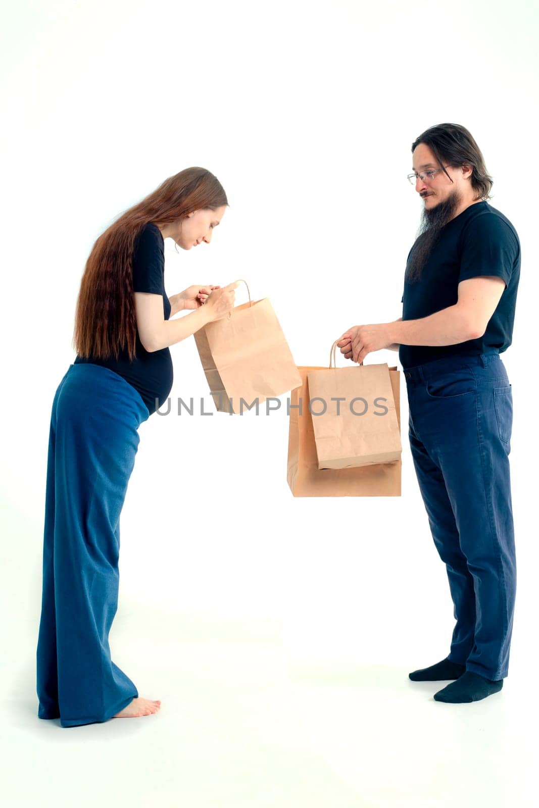 Portrait happy young pregnant woman and her husband with shopping bags and touching her big belly isolated on white background. Pregnancy shopping concept happy young family with shopping bags