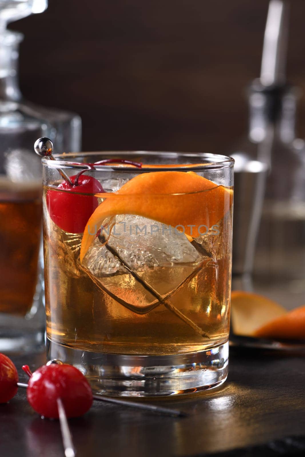 Cocktail Old Fashioned is an old-fashioned sophistication of whiskey and sweet syrup. Served with ice, orange zest and Maraschino cherry. 