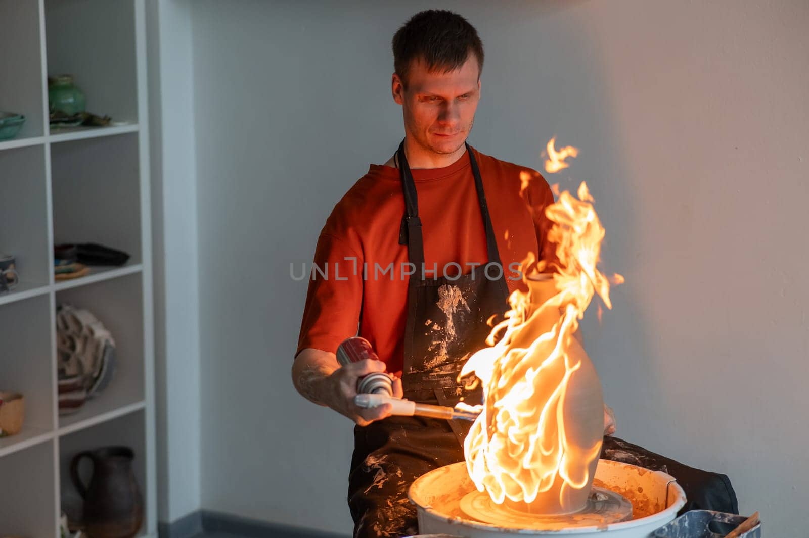 A potter burns a jug with a gas burner on a potter's wheel. by mrwed54