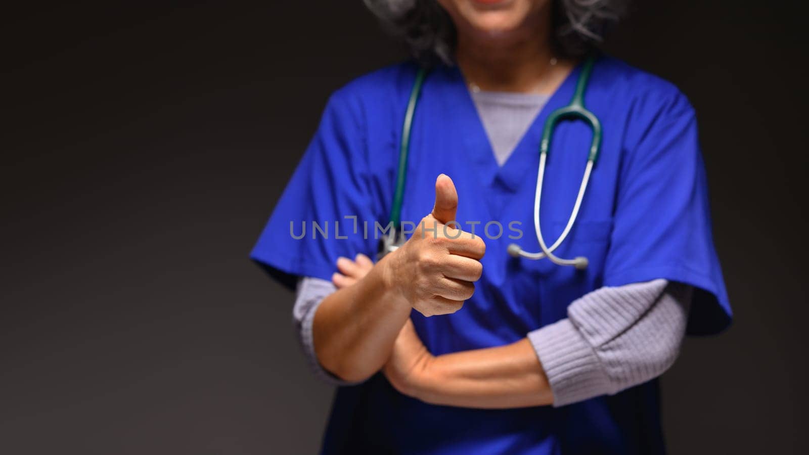 Senior doctor with stethoscope showing thumbs up over black background . Medical and health care concept.