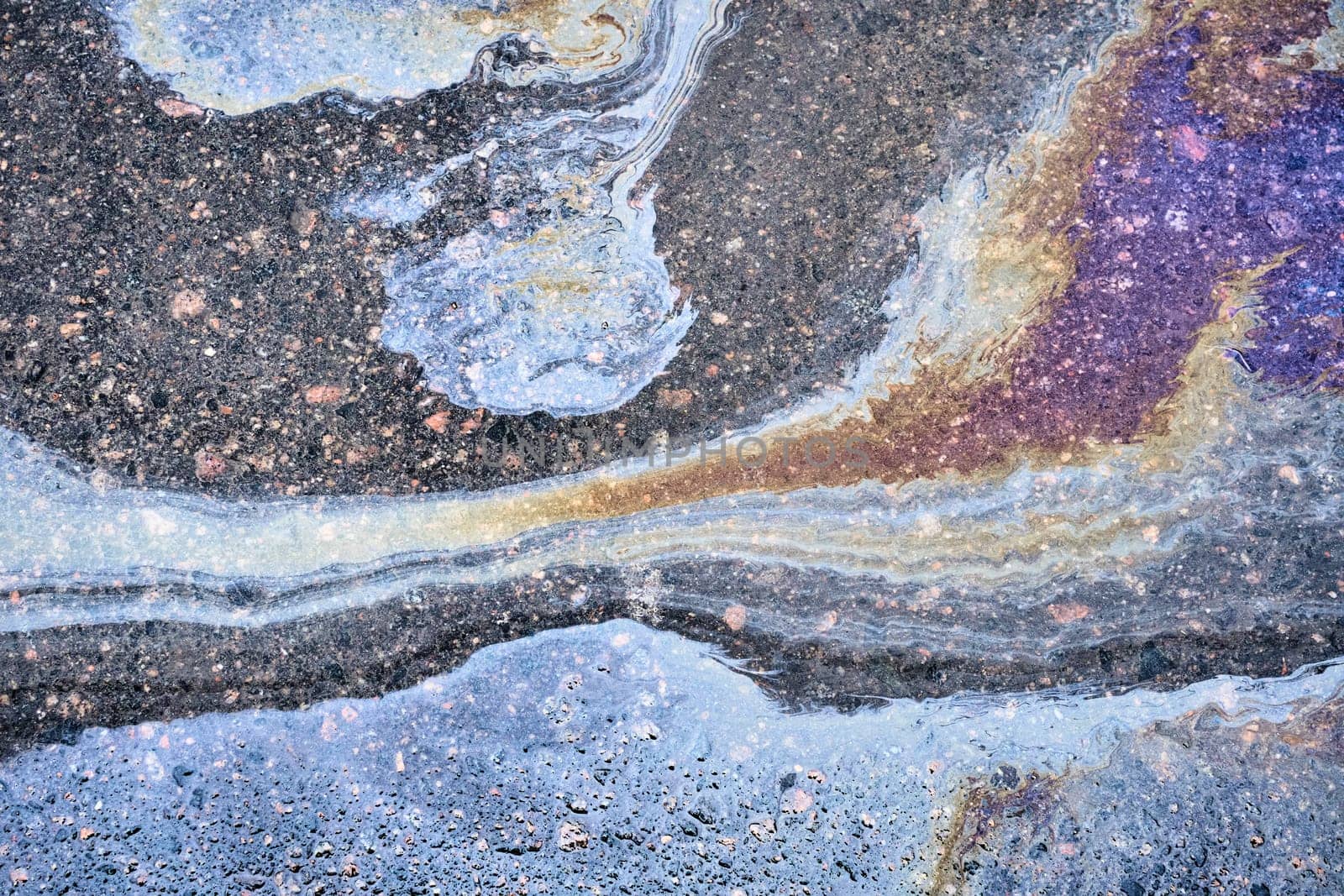 An overhead shot of the mesmerizing patterns created by leaking gasoline on wet ground. by AliaksandrFilimonau