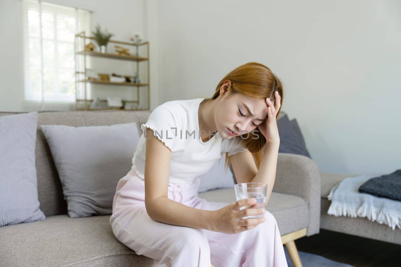 Unhappy sick young asian woman suffer from terrible head pain. touching her head while suffering from a migraine by itchaznong