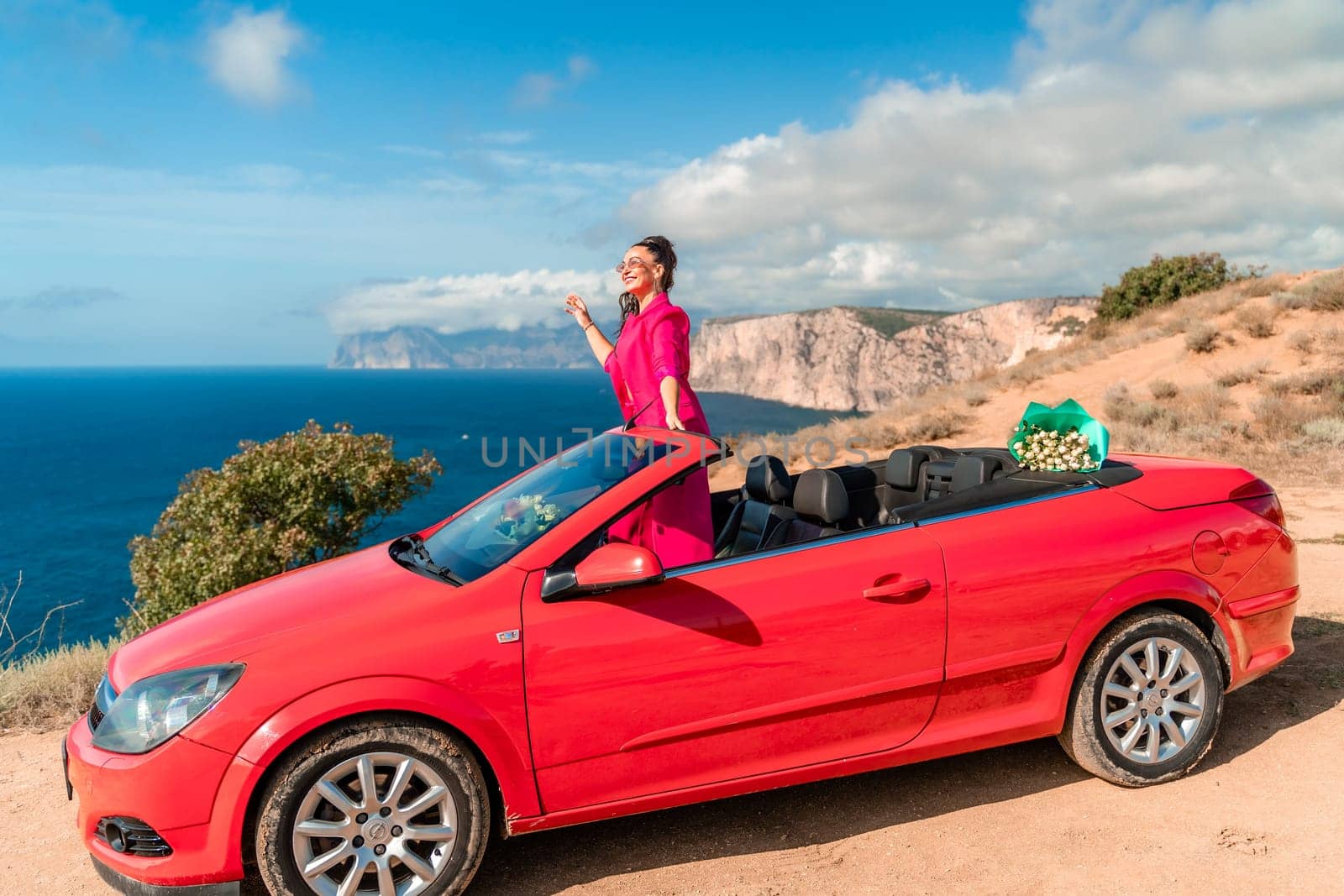 A woman is posing on top of a red car. She is wearing a pink suit and sunglasses. by Matiunina