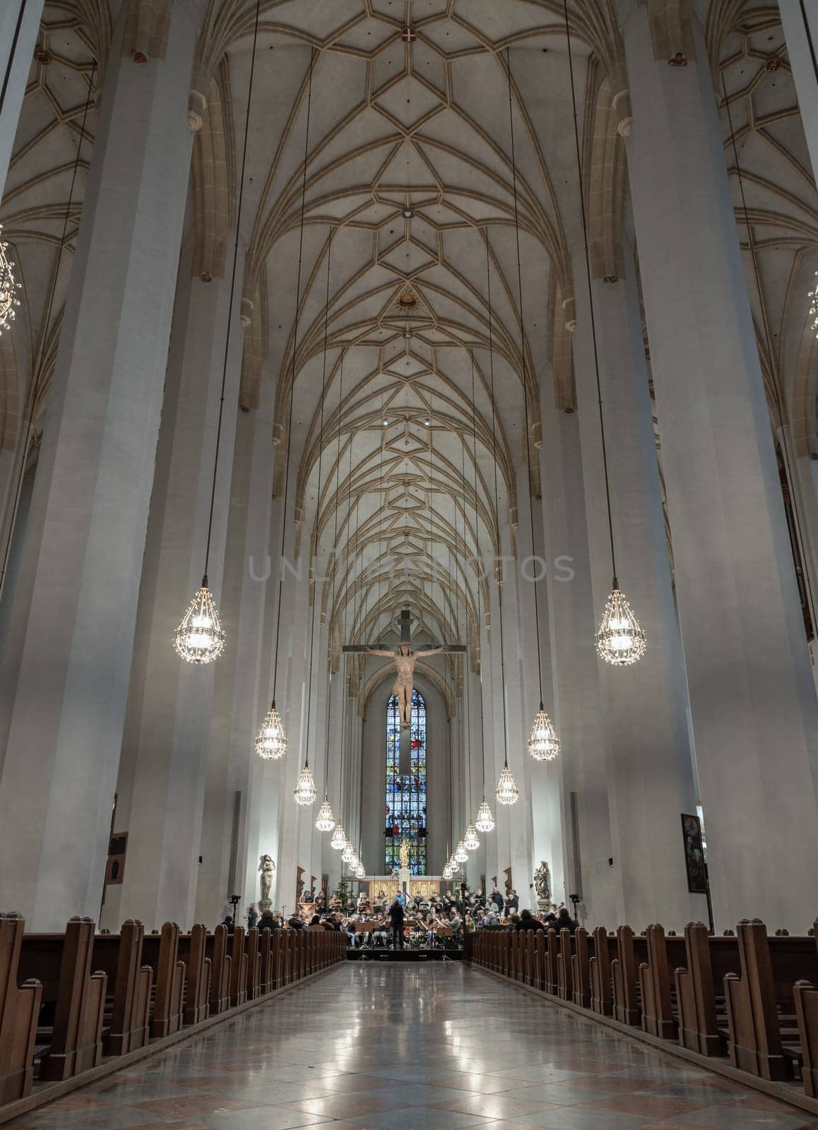 Munich, Germany - Dec 21, 2023 - Symphony Orchestra concert in Frauenkirche. Jesus hanging on the cross in the interior of Cathedral Church of Our Lady, Architecture interior is the most iconic of Munich. Space for text, Selective focus.