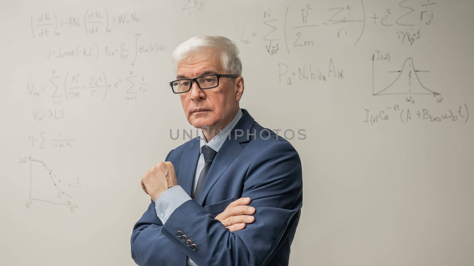 Mature man stands at a white board with written formulas. by mrwed54
