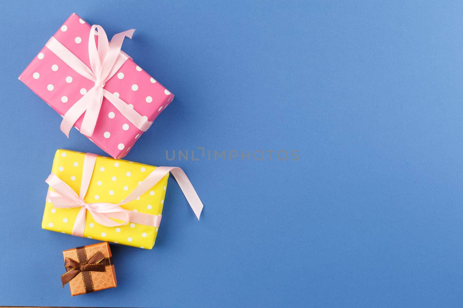 Presents in colorful wrapping paper with ribbon bows on blue isolated background. Flat lay. Festive gift concept. Top view.