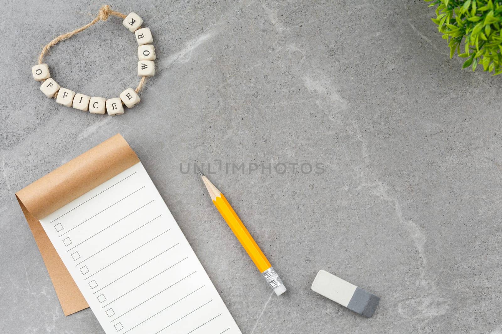 Open notepad, pencil and potted plant on gray marble background. Top view. Office desk concept.